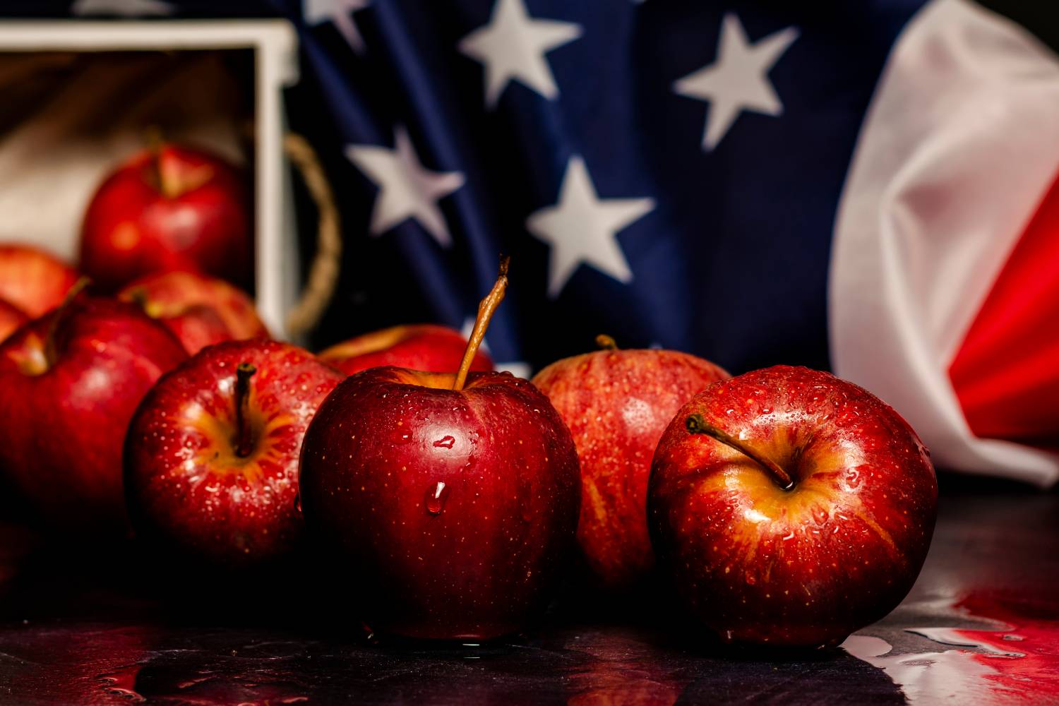 Apples on a table with the American flag in the background.