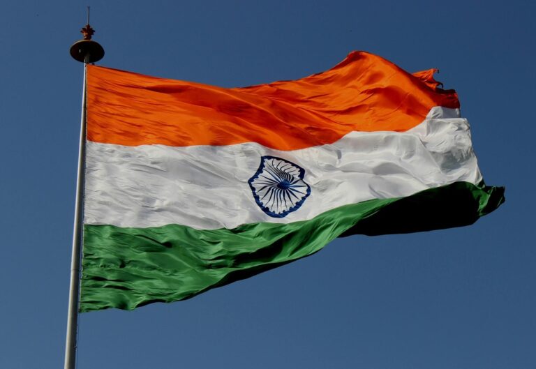 Indian flag waves up a mast against a blue sky