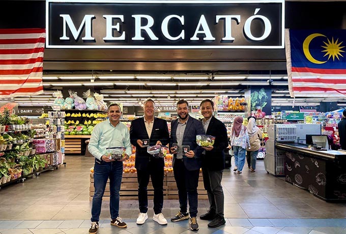 Four men, two of then SanLucar executives, pose for a picture in front of the store logo of Malaysian grocery store, Mercato