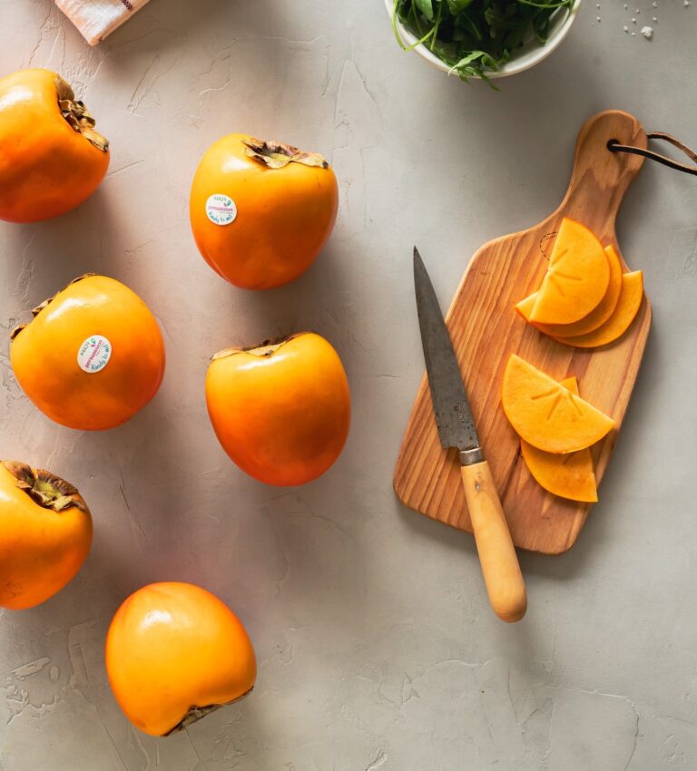 Kaki persimmons ON TABLE NEXT TO CUTTING BOARD