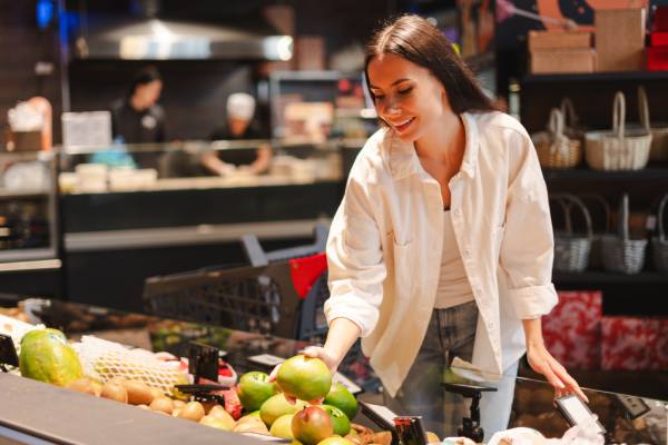 person choosing mango at grocery store